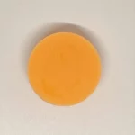 Étiquette du fondant parfumé 'Monoï de Tahiti' à la cire de soja. L'illustration est une photo d'un tube de crème solaire sur le sable, évoquant le parfum solaire et exotique des vacances